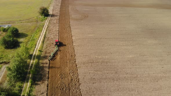 A Farmer on a Tractor Uses a Harrow Seeder, Cultivates the Soil, Prepares the Fields for Sowing