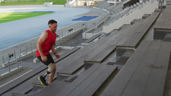 Caucasian disabled male athlete with prosthetic leg training, running up stairs