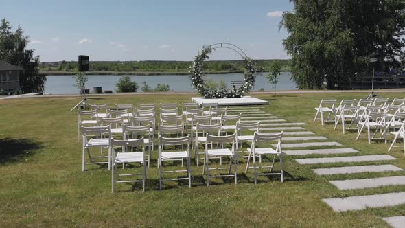 Aerial View of a Flower Arch and a Row of Chairs for Guests of a Wedding Ceremony on the Banks of