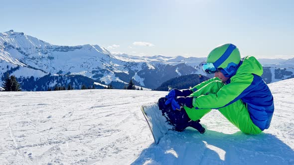 Boy Attaching Snowboard Sit in the Snow on Ski Track