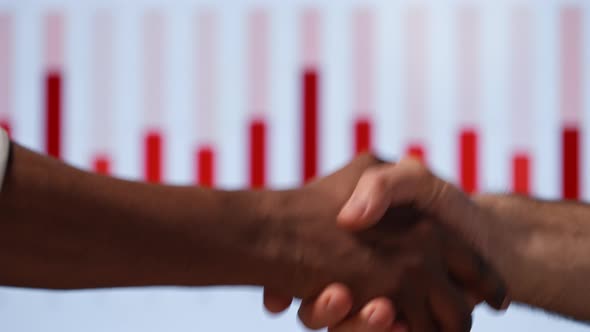 Two businessmen shaking hands against multimedia background with graphs