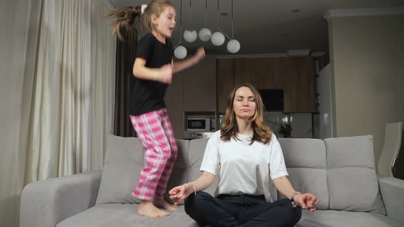 Mother Does Yoga While Daughter Distracts Jumping on Sofa