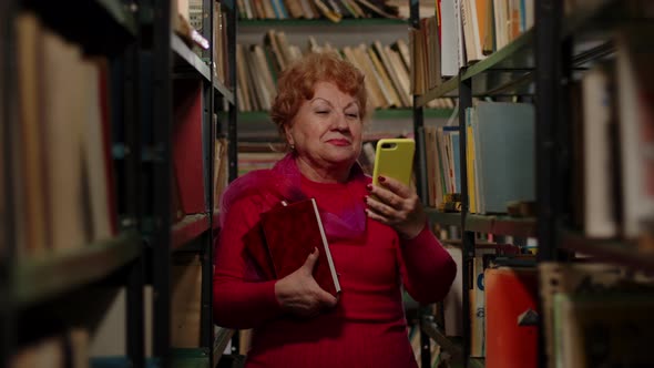 An Elderly Woman Takes a Photo with Books in the Library