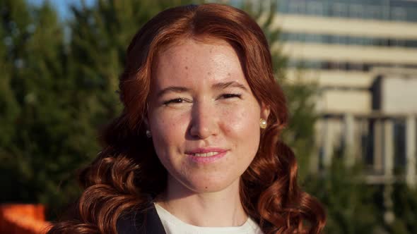 Attractive Woman with Curly Hair Smiles to Camera on Street