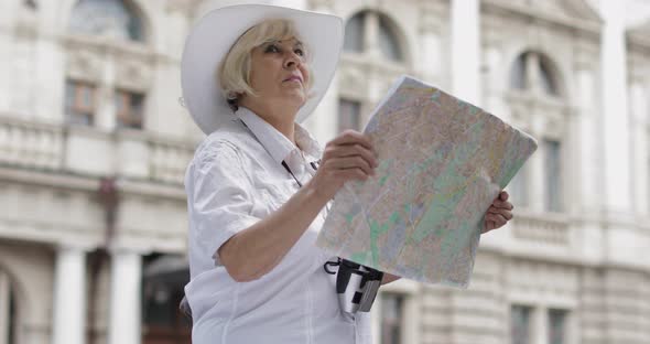 Senior Female Tourist Exploring Town with a Map in Hands, Looking for the Route