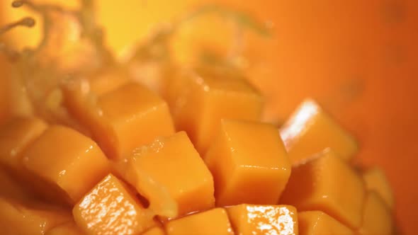 Slow Motion Shot of Mango Juice Splashing Through Mango Cube Slices