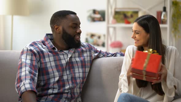 Caucasian Girl Giving Gift Box to Her Afro-American Boyfriend, Birthday Greeting