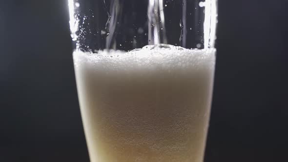 Light Beer is Poured Into a Glass Closeup on a Black Background