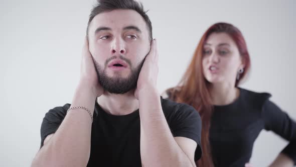 Close-up Face of Annoyed Handsome Brunette Man with Brown Eyes Closing Ears with Hands As Blurred