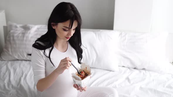 Pregnant Woman Eating Chinese Food At Home In Bed