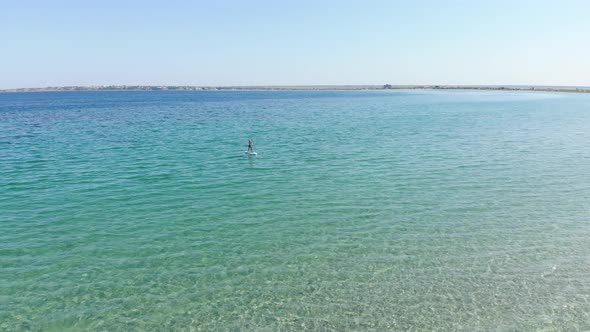 A Young Woman on a Paddleboard is Exercising in the Morning