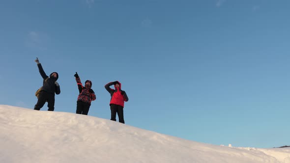 Travelers Come To Top of Snowy Hill and Rejoice at Victory Against Backdrop of a Yellow Sunset