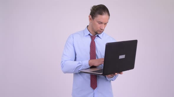 Happy Handsome Businessman Thinking While Using Laptop