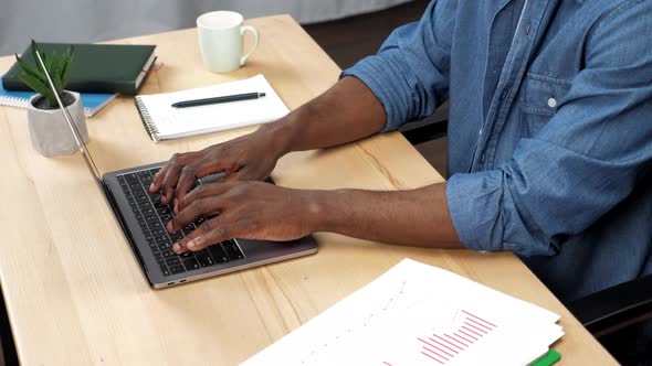 African American Man Works for Laptop Typing on the Keyboard in Office