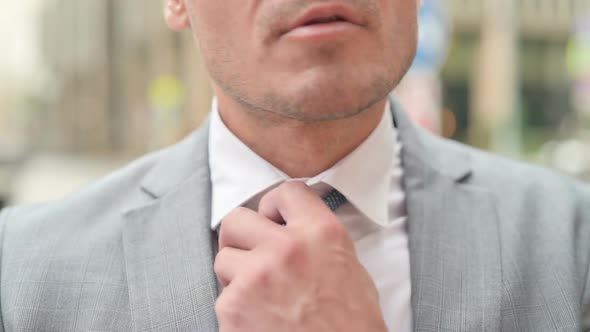 Close up of Middle Aged Businessman Opening Neck Tie