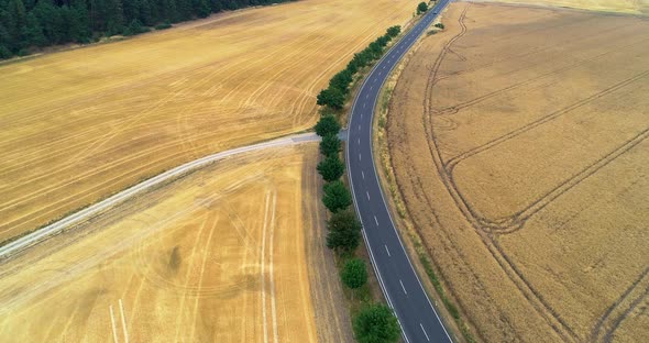 Aerial Fly Over The Road Between Agriculture Fields With Cars Moving