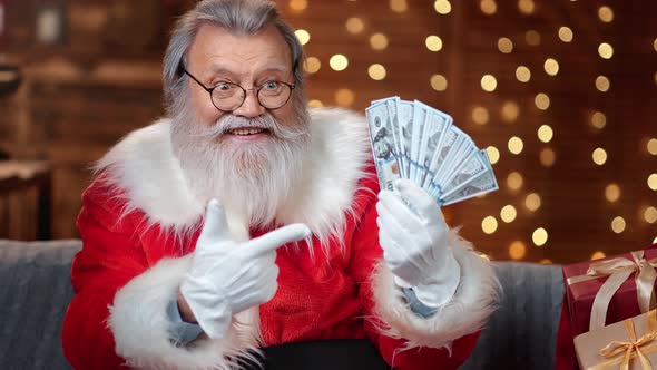 Portrait of Male Santa Claus with Natural Beard Pointing on Cash Money Fan