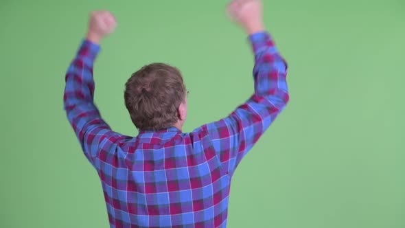 Rear View of Happy Overweight Bearded Hipster Man with Fists Raised