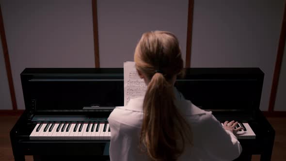 Woman sensually playing the piano view from the back