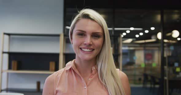 Caucasian businesswoman walking looking at camera and smiling in modern office