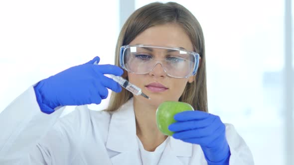 Female Doctor, Scientist Injecting Apple with Chemical, Reaction alt