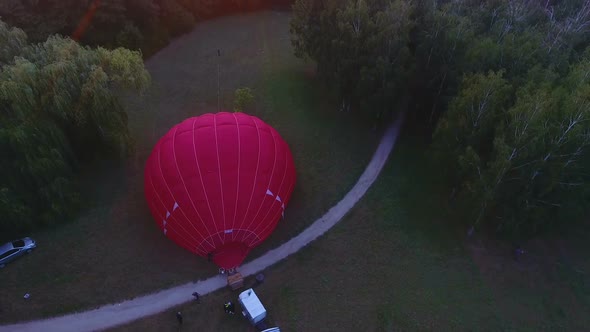 Workers Inflating Hot Air Balloon Envelope on Ground, Sun Rising on Horizon