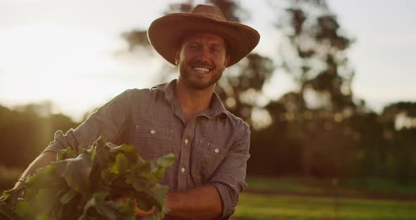 Portrait of young farmer holding his harvest at sunset