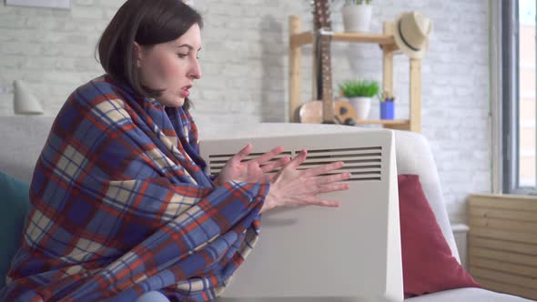 Young Woman Freezes in the Living Room and Heats Herself Next To an Electric Heater