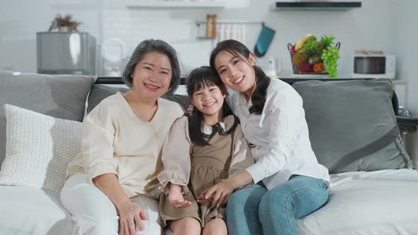 Portrait of Asian family, kid mother and grandmother smile, sitting together in living room at home.