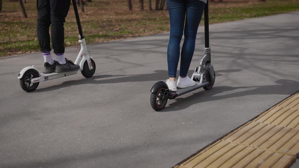 A Man and a Woman Ride Electric Scooters