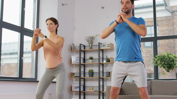 Happy Couple Exercising and Doing Squats at Home