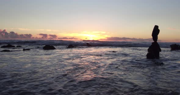 Stunning view of the sunset at low tide in Laguna Beach as the sun peaks out amongst rocks and refle