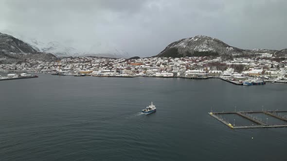 Fishing boat cruising past salmon pens arriving back at Skjervoy harbor, Norway