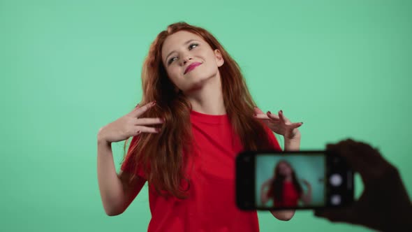 Smiling Vlogger Woman Recording Video of Herself Dancing in Front of Smartphone Camera on Green