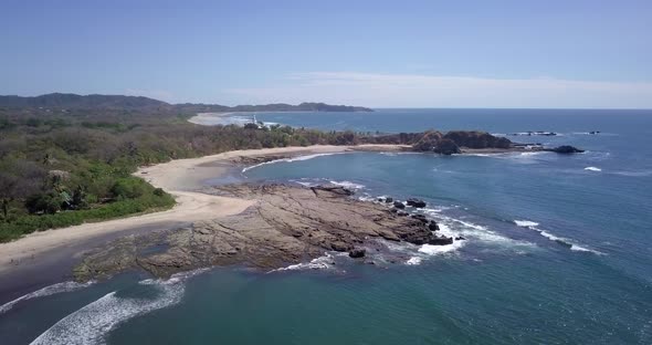 Aerial drone view of the beach, rocks and tide pools in Playa Palada, Guiones, Nosara, Costa Rica.