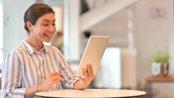 Serious Latin Woman with Laptop Talking on Smartphone at Home