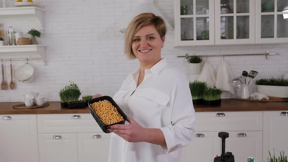 Portrait of a Young Woman with a Box of Sprouted Peas in Her Hands