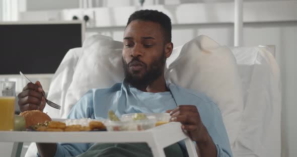 African Male Patient in Hospital Bed Eating Meal From Tray