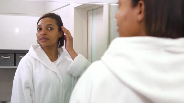 A Young Beautiful Woman Looks in the Mirror and Adjusts Her Hair