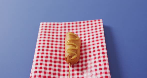 Video of corn dog with mustard on a blue surface