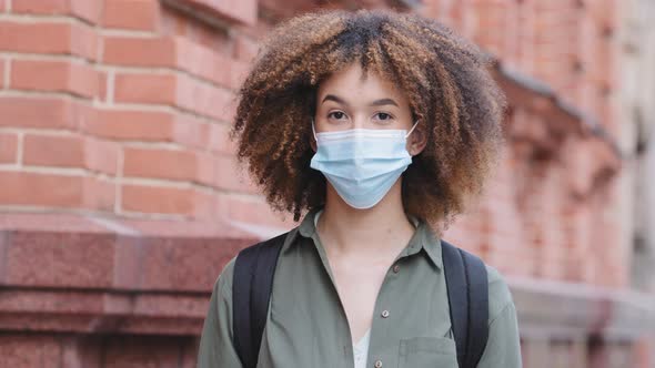 Headshot Portrait African American Young Woman in Blue Protective Medical Face Mask Standing Against