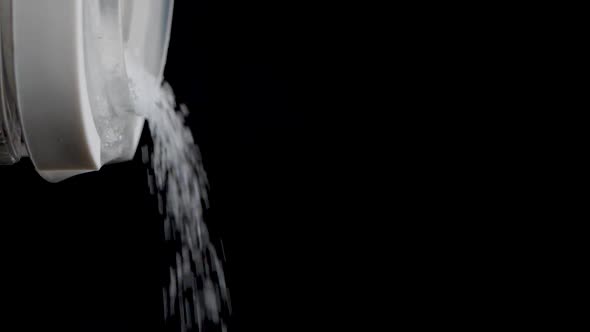 Close up shot of pouring out sugar out of a transparent container in slow motion.