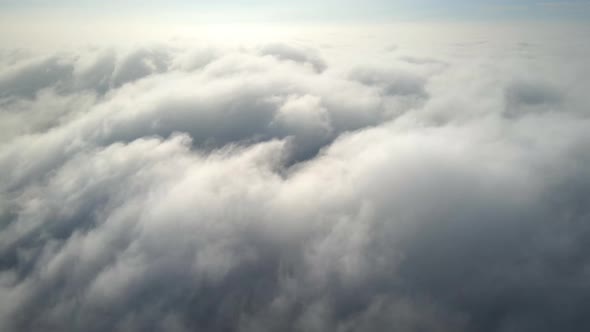 Aerial shot of flying over a layer of soft clouds at dawn