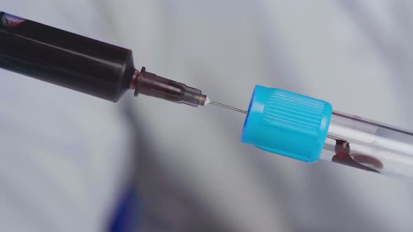 Doctor Pours Blood From a Syringe to Test Tube Close Up