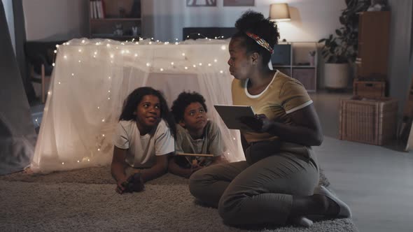 Woman Reading to Kids in Blanket Fort