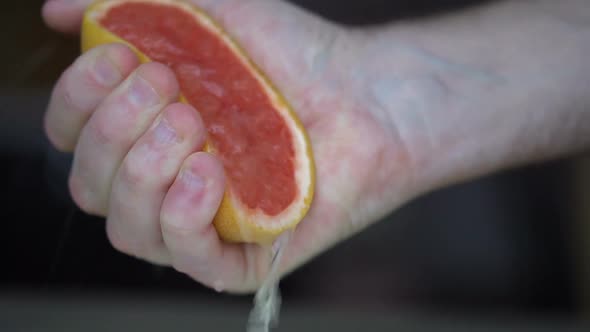 Male Hands are Squeezing Ripe Grapefruit for Making Citrus Juice  Healthy Lifestyle Fruit Juice