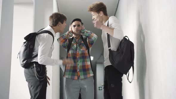 Stressed Caucasian Boy Closing Ears with Hands As Angry Friends Yelling at Front