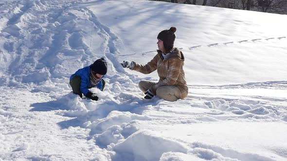 Asian Mother And Her Son Playing Snow Together In The Park 