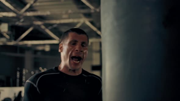 Sweaty Face Closeup of an Athlete in Boxing Gloves Hitting a Punching Bag
