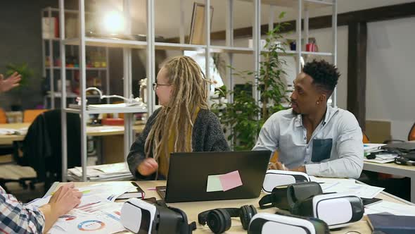 Reative Group Working at Office Table and Giving High Five to Greet their Male Colleague